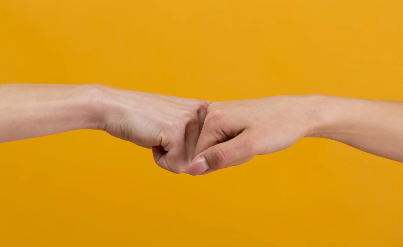 Two hands fist bumping representing people discussing politics in the workplace harmoniously