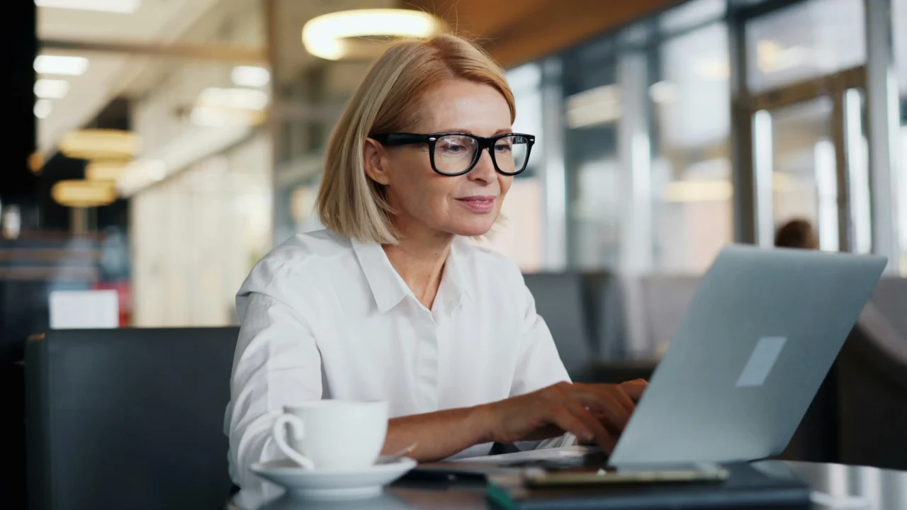 A professional woman using a laptop to communicate PTO in a plush office.