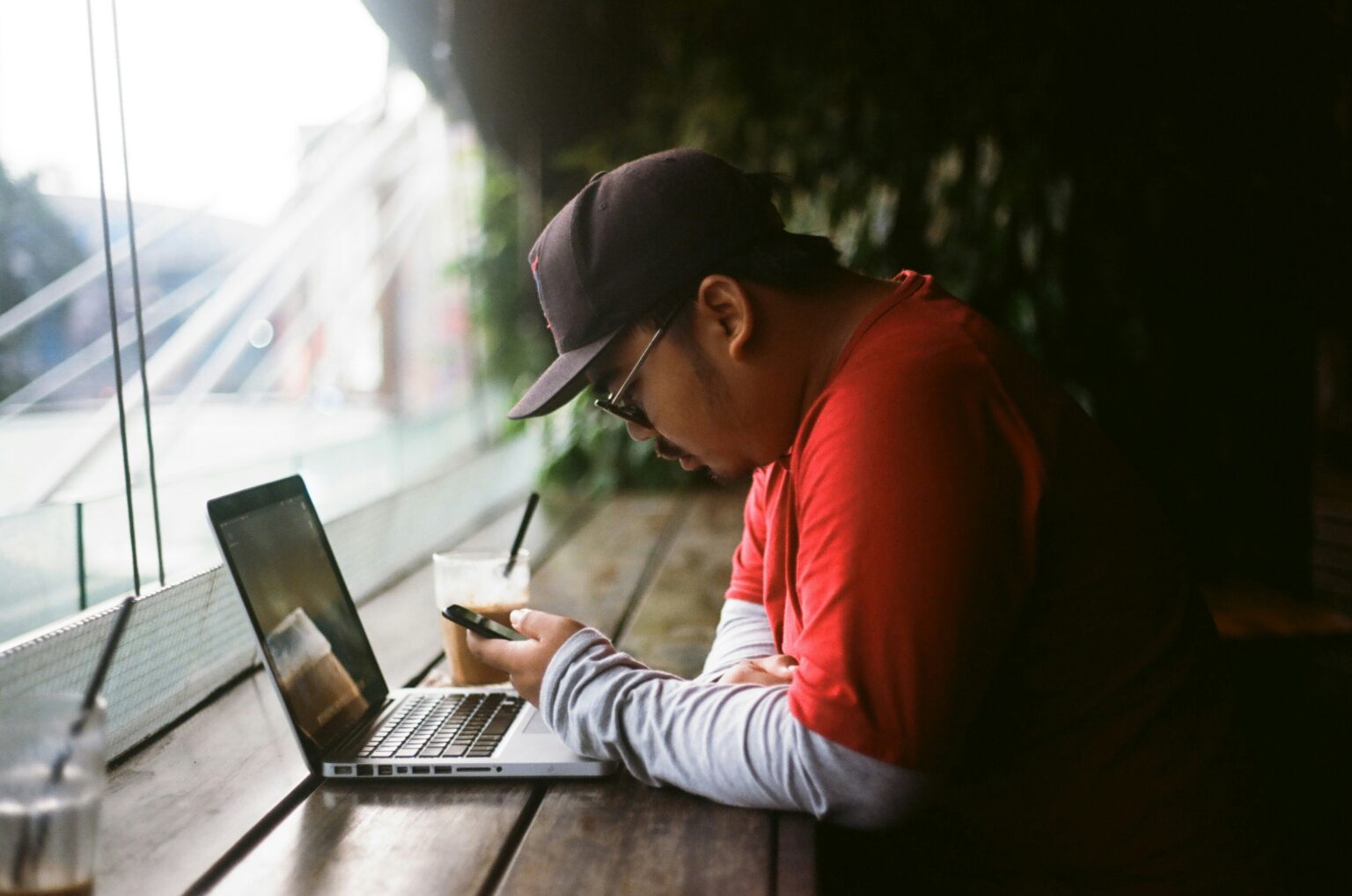 Young man leaning over laptop at wooden counter top.