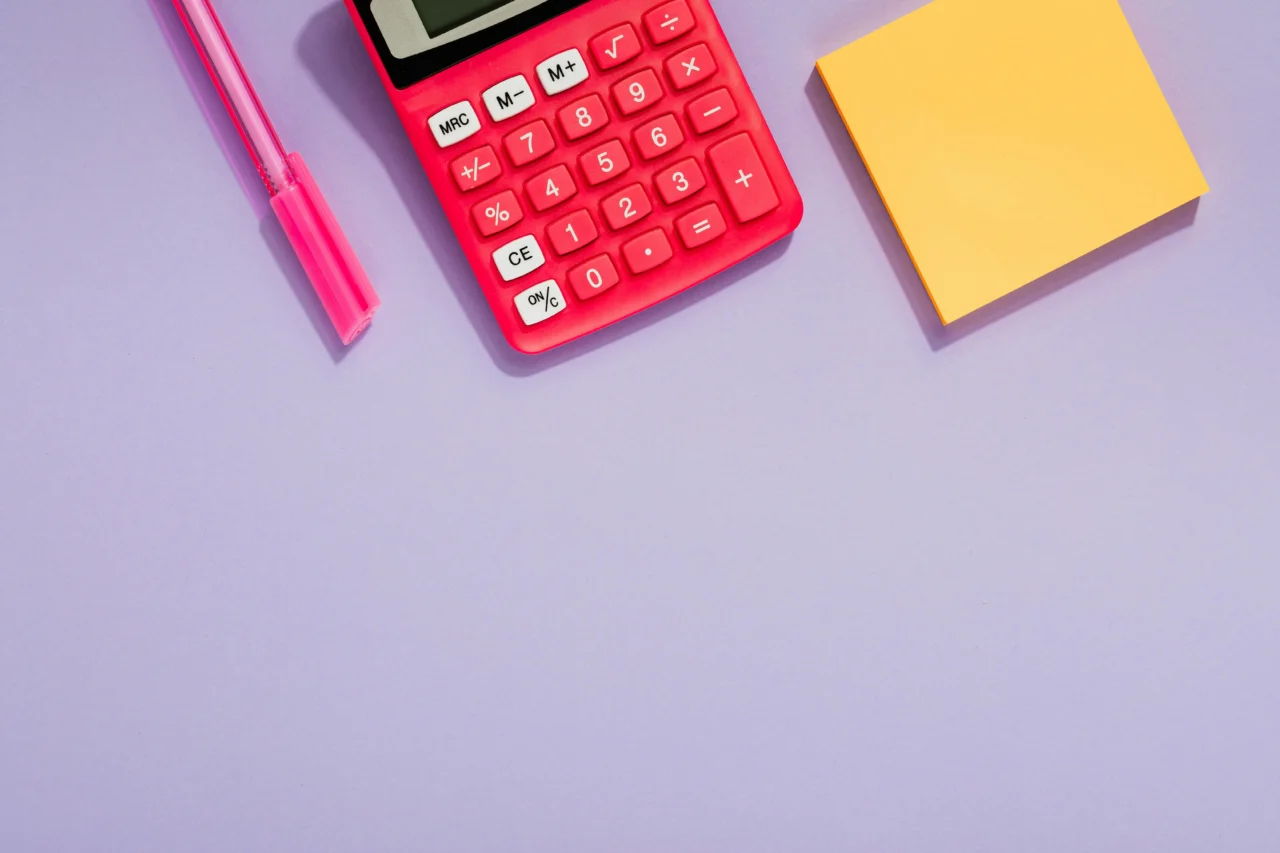 A calculator, pen, and sticky note pad for calculating employee ROI