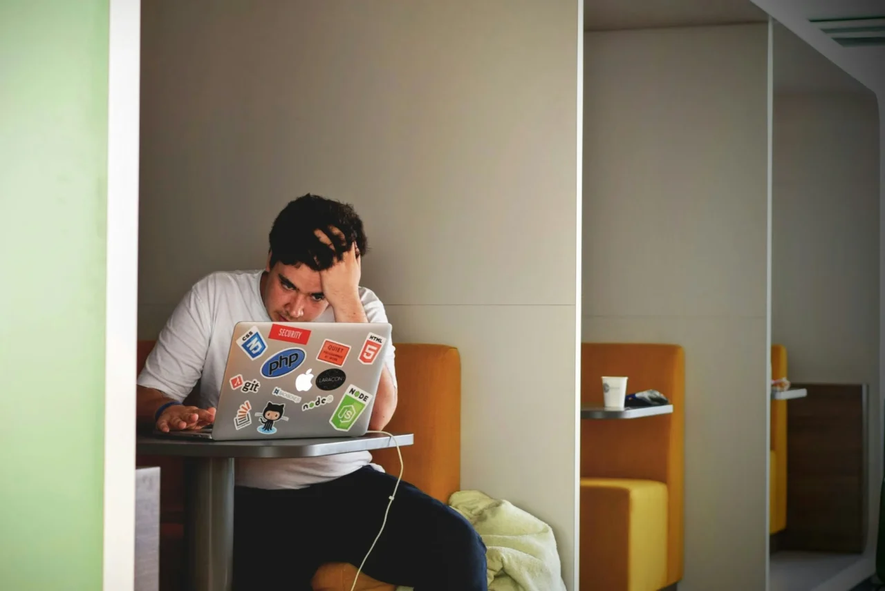 Man in a work seating booth sitting with a laptop.